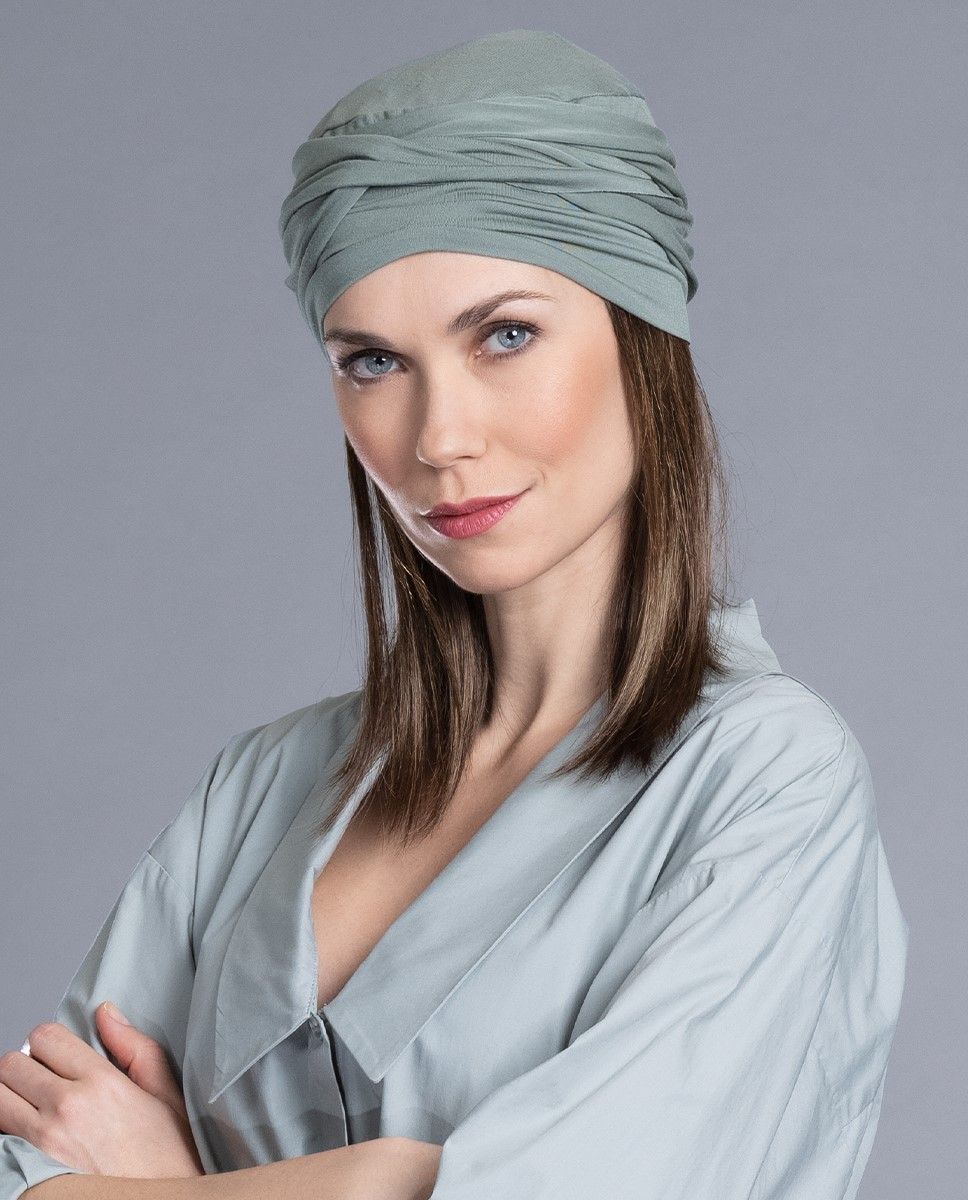 Frau mit blauen Augen und Turban, die Arme verschränkt, trägt ein hellblaues Gewand.