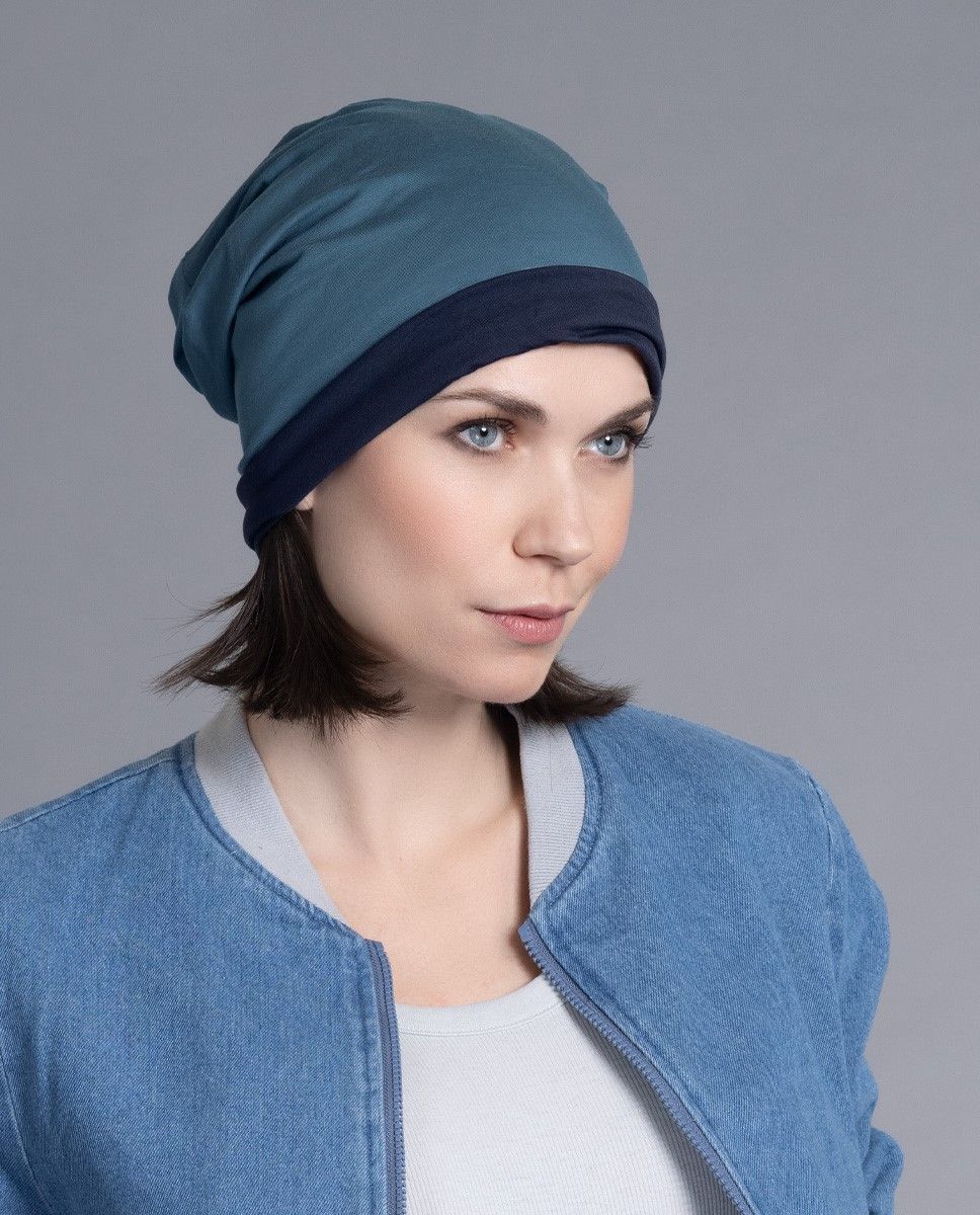 Frau trägt eine blaugrüne und marineblaue Mütze und eine Jeansjacke.