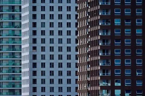 Cuatro edificios modernos de gran altura en diferentes colores y estilos arquitectónicos, con filas de ventanas.
