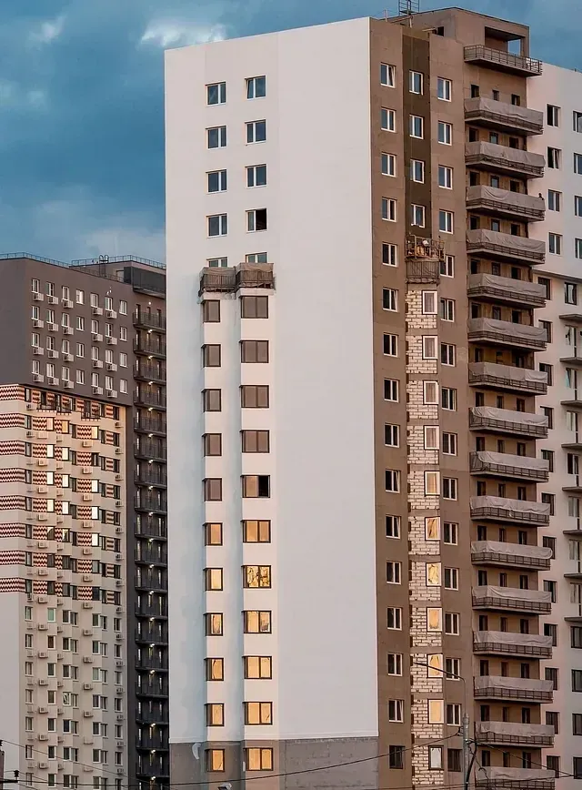 Edificios altos de apartamentos de varios pisos en construcción; exterior con fachadas blancas y beige, ventanas.