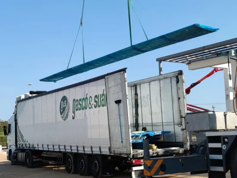 Un camión semirremolque blanco está estacionado frente a un muelle de carga.
