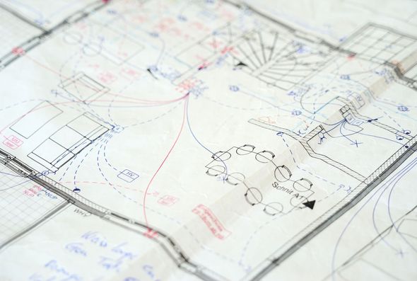 Person, die an der Verkabelung eines Solarmoduls arbeitet; blaue und rote Kabel, Außenbereich.