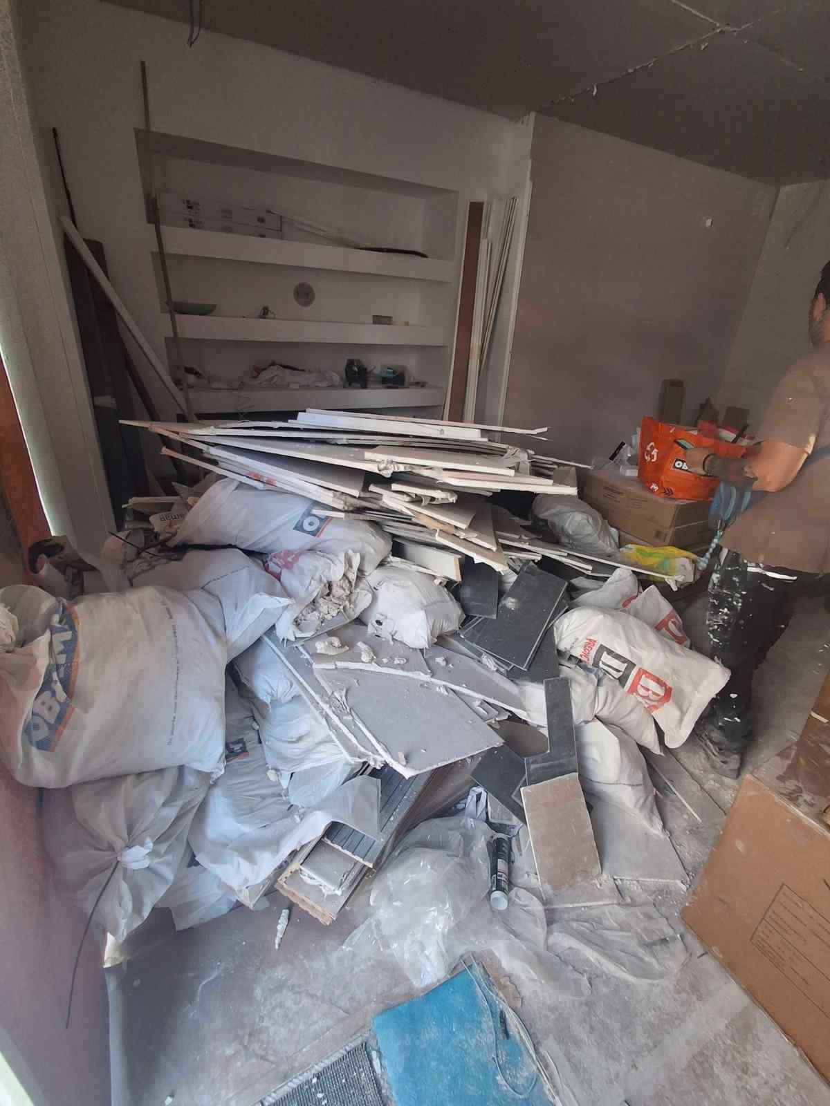 Habitación desordenada, llena de montones de escombros blancos y grises, cajas y materiales de construcción.
