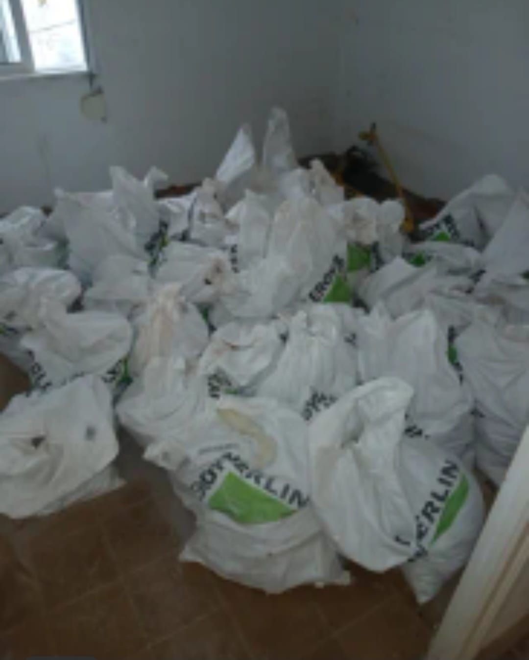 Muchas bolsas de plástico blancas apiladas en el suelo de una habitación