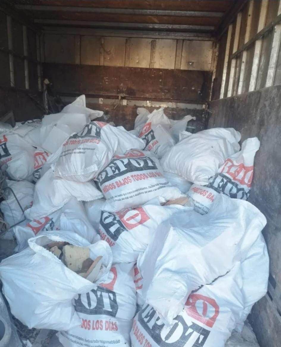 Caja de una camioneta llena de sacos blancos de mercancías, apilados dentro de un remolque de carga