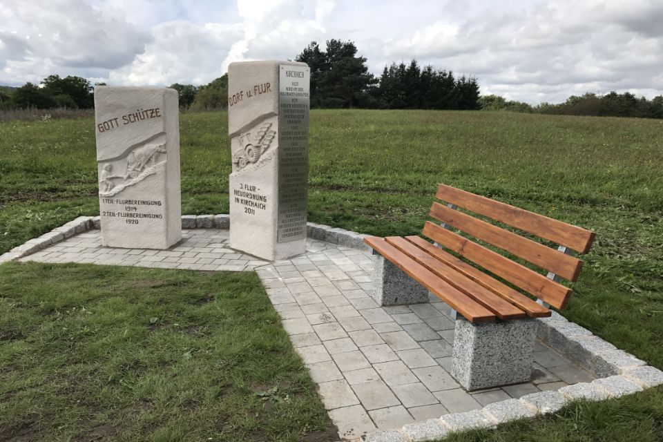 Holzbank auf Terrasse aus Naturstein umgeben von Wiese