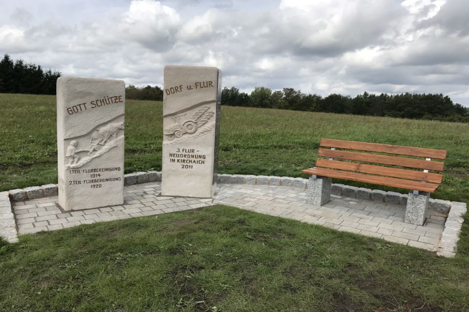 Holzbank auf Terrasse aus Naturstein umgeben von Wiese