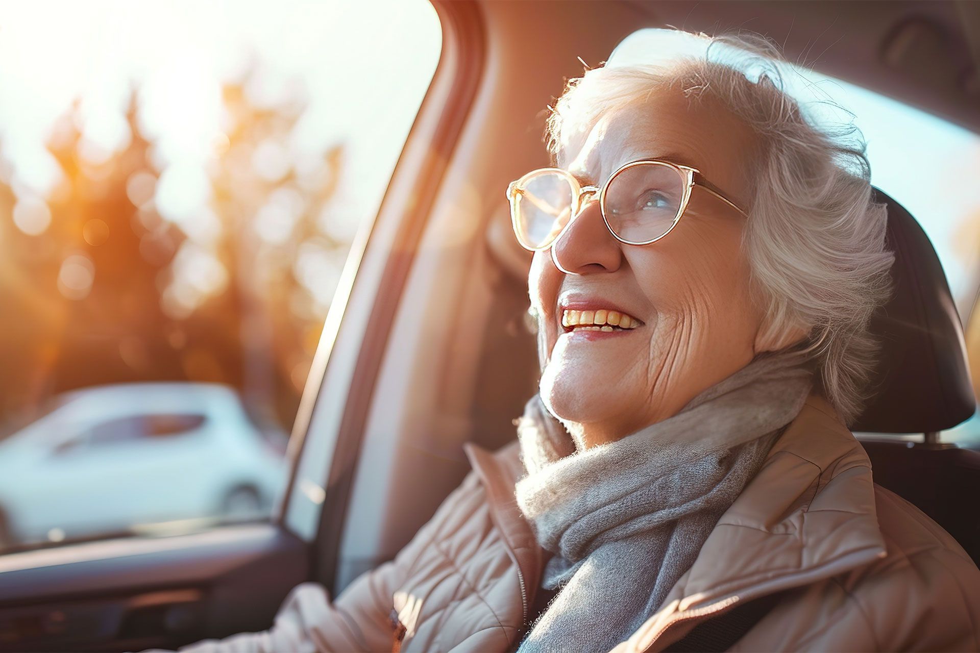 Eine ältere Frau mit Brille sitzt auf dem Fahrersitz eines Autos.