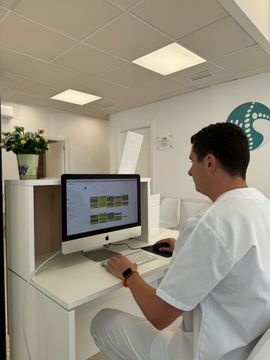 Un hombre está sentado en un escritorio frente a una computadora.