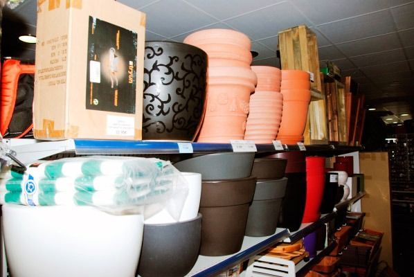 Hay un montón de macetas en un estante de una tienda.