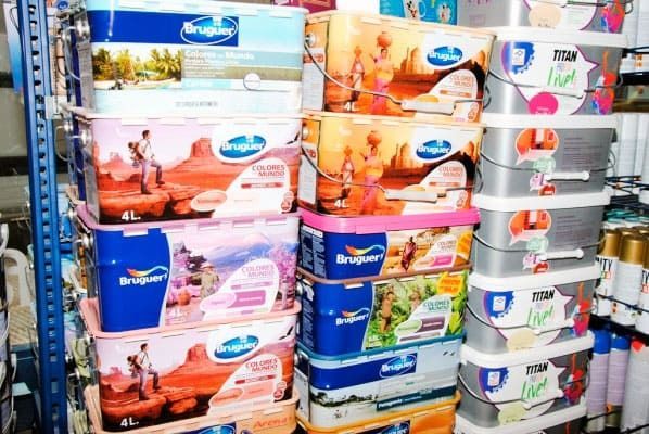 Un montón de cubos de pintura están apilados uno encima del otro en un estante.