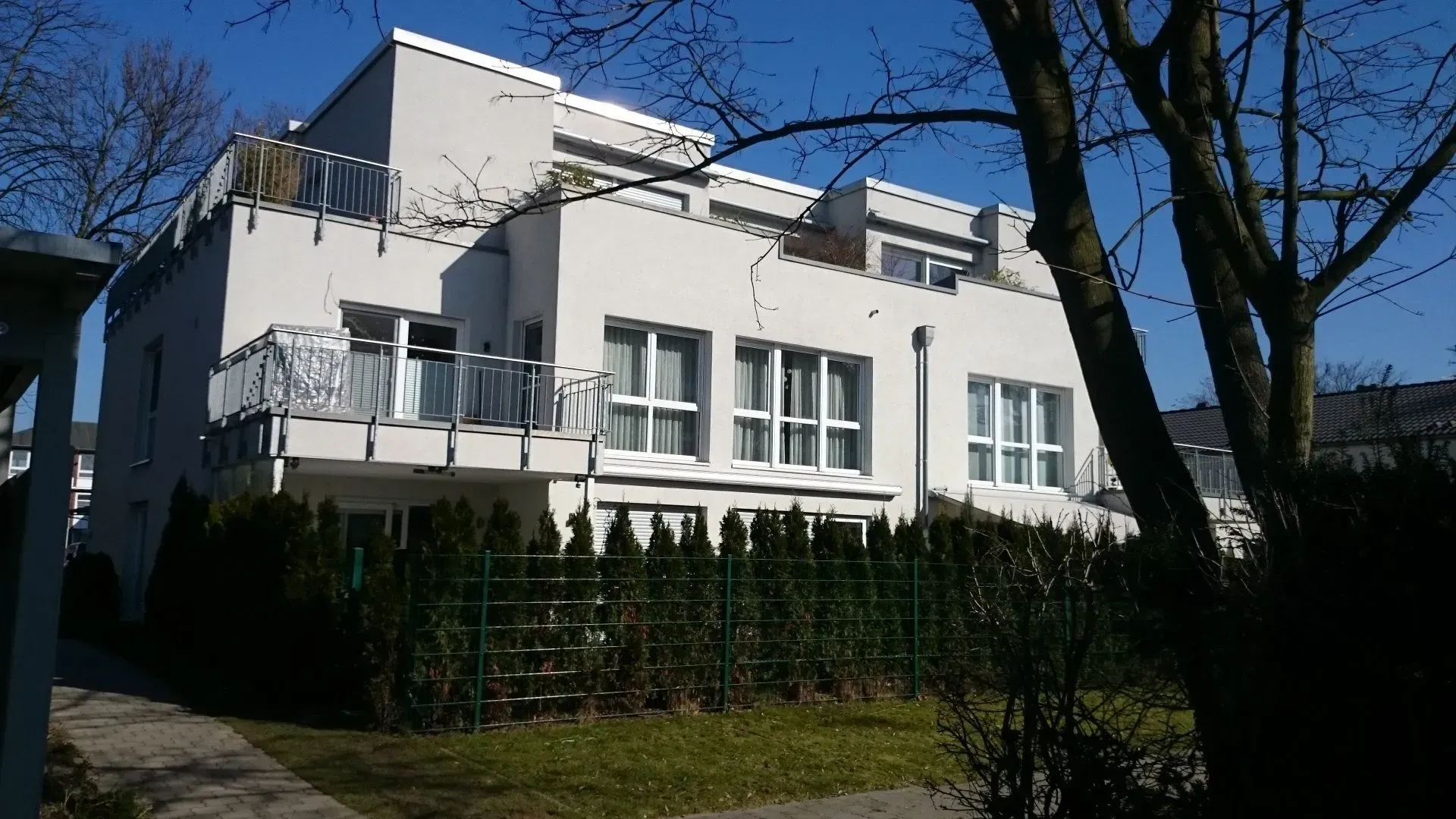 Ein modernes großes Haus mit wenigen Wohnungen, vielen Fenstern und großen Balkonen, im Neubaugebiet