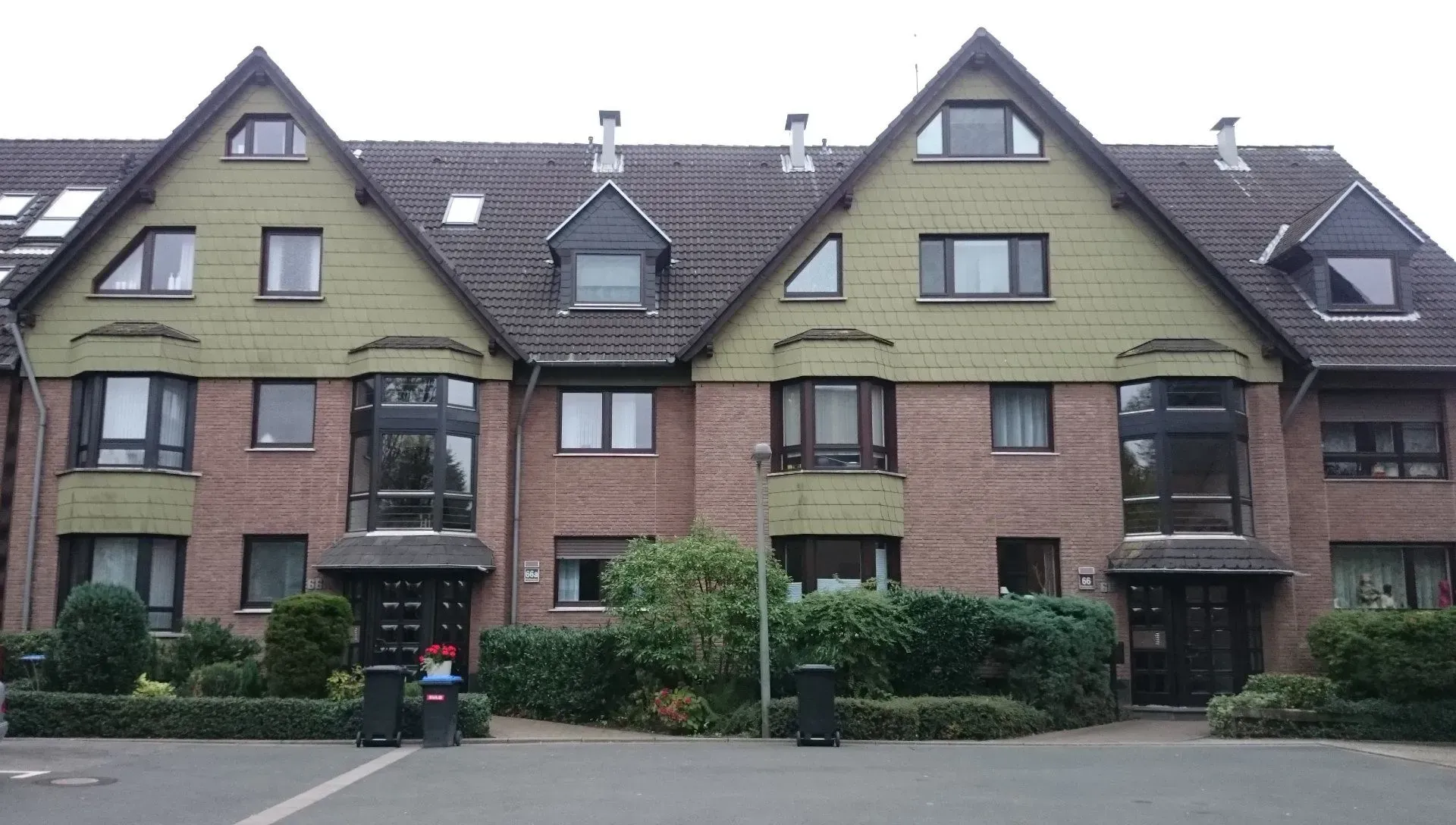 Eine Reihe von Altbau-Wohnhäusern mit grüner Außenverkleidung