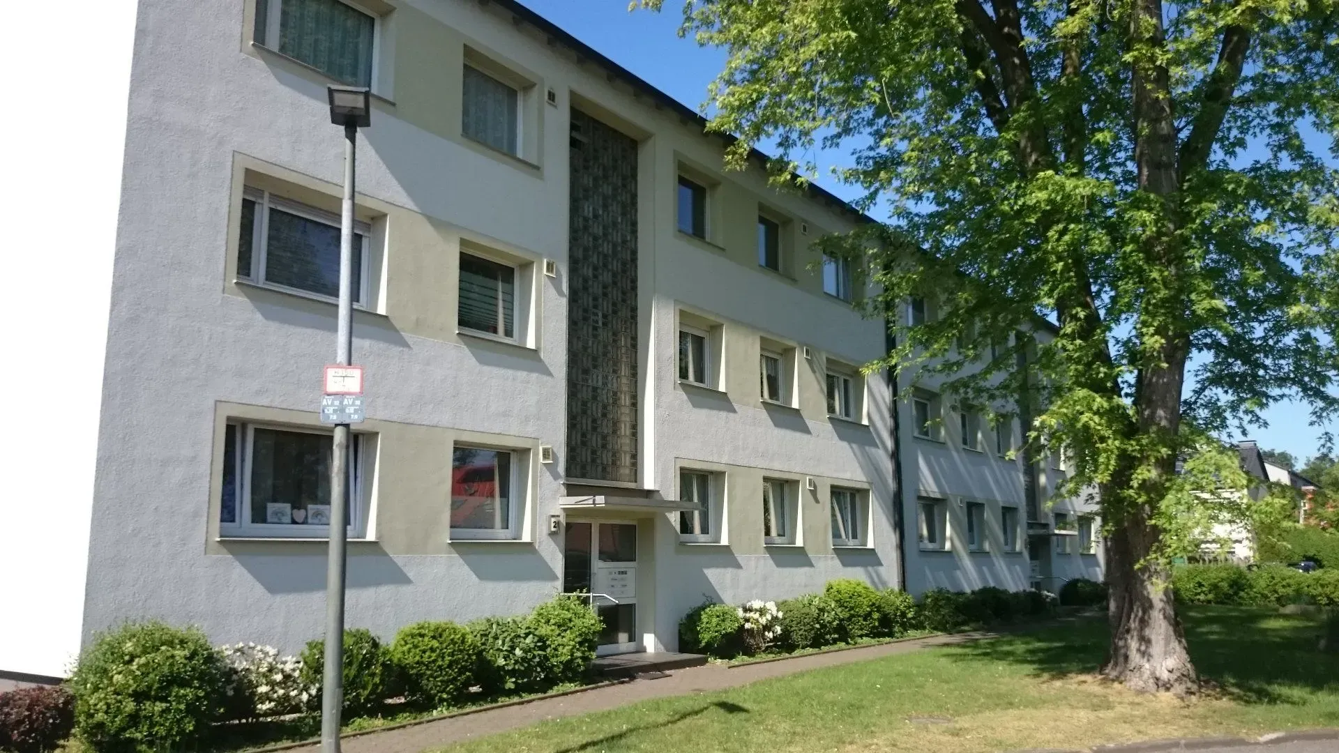 Ein weißes Mehrfamilienhaus mit einem Baum davor
