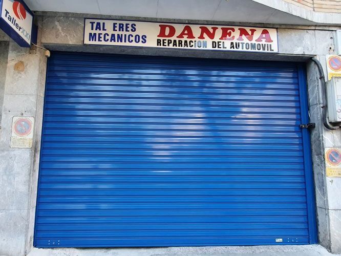 Una puerta de garaje azul con un cartel encima que dice talleres mecanicos danena