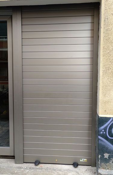 Una puerta de garaje gris está sentada al costado de un edificio.