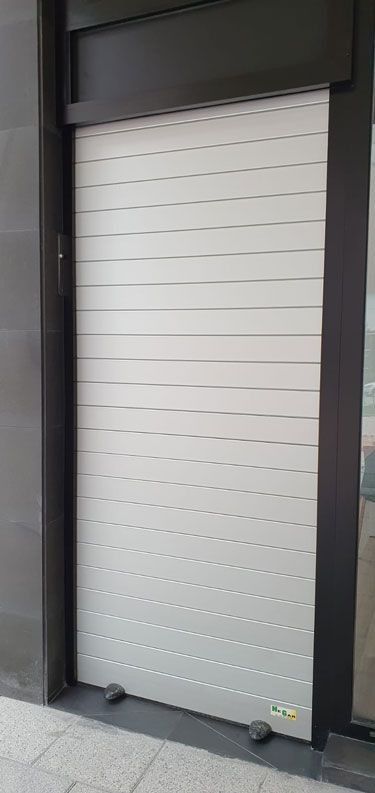 Una persiana blanca está cerrada en el lateral de un edificio.