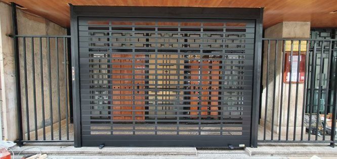 Una puerta de garaje negra con una valla alrededor.