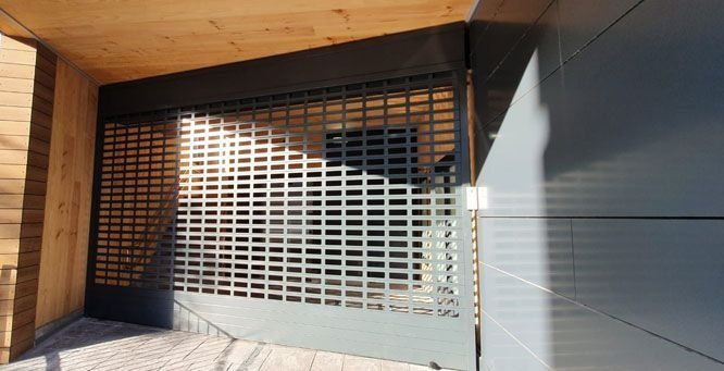 Una puerta de garaje con reja está al lado de un edificio de madera.