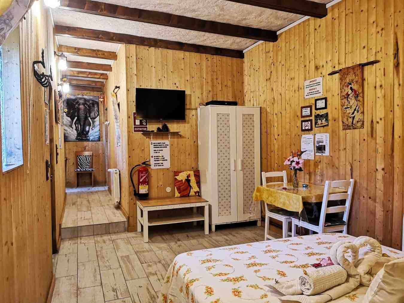 Acogedor interior de cabaña con paneles de madera. Incluye cama, televisor
