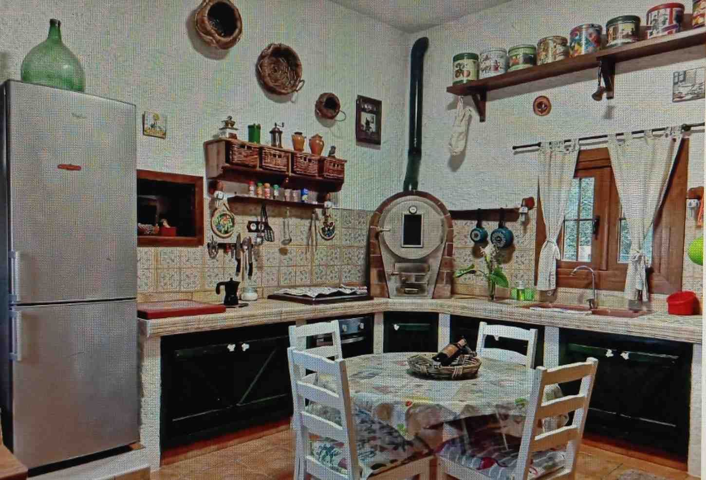 Cocina con refrigerador, estufa, estantes de especias y mesa redonda con sillas.