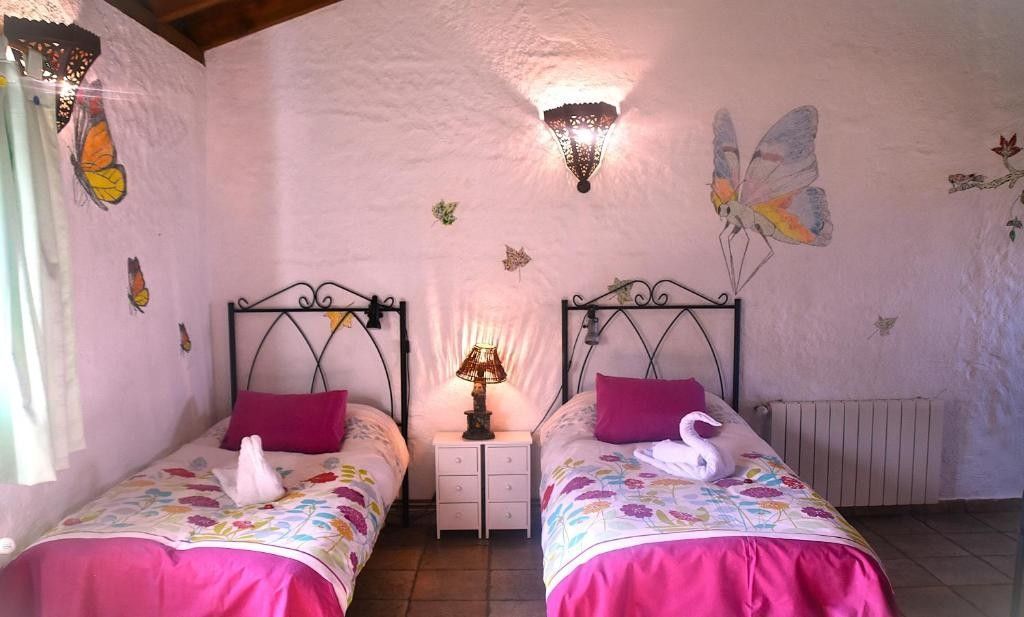 Dos camas individuales en un dormitorio con murales de mariposas.