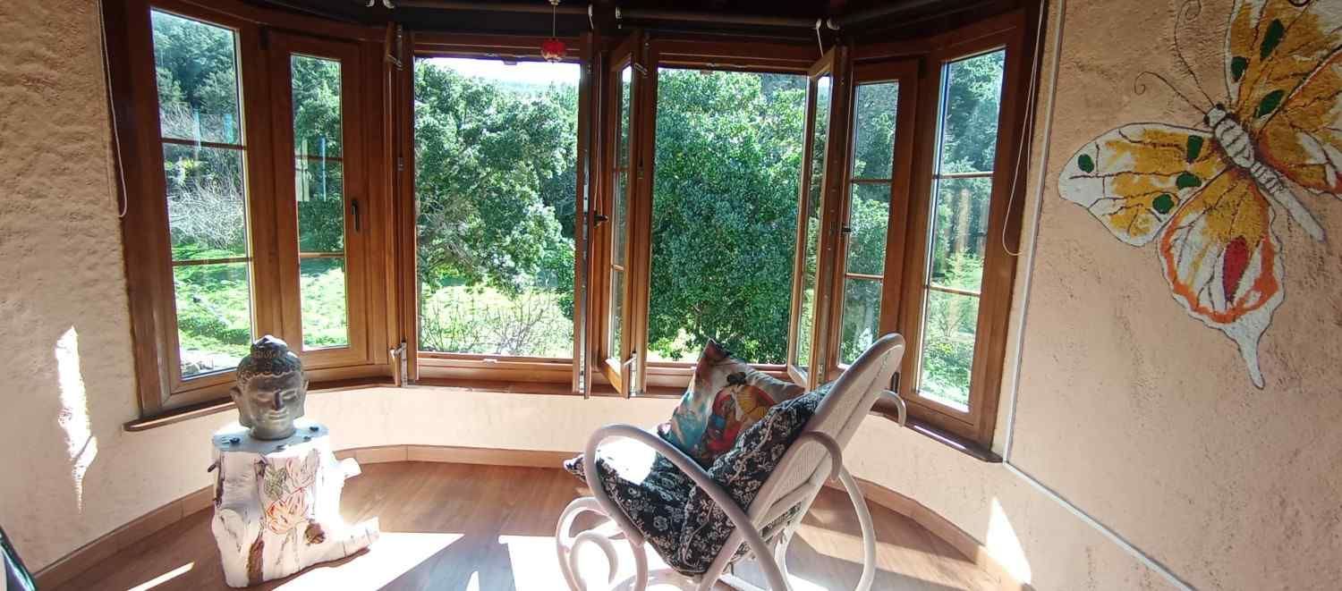 Interior de solárium con ventanas con marco de madera. Una silla de mimbre