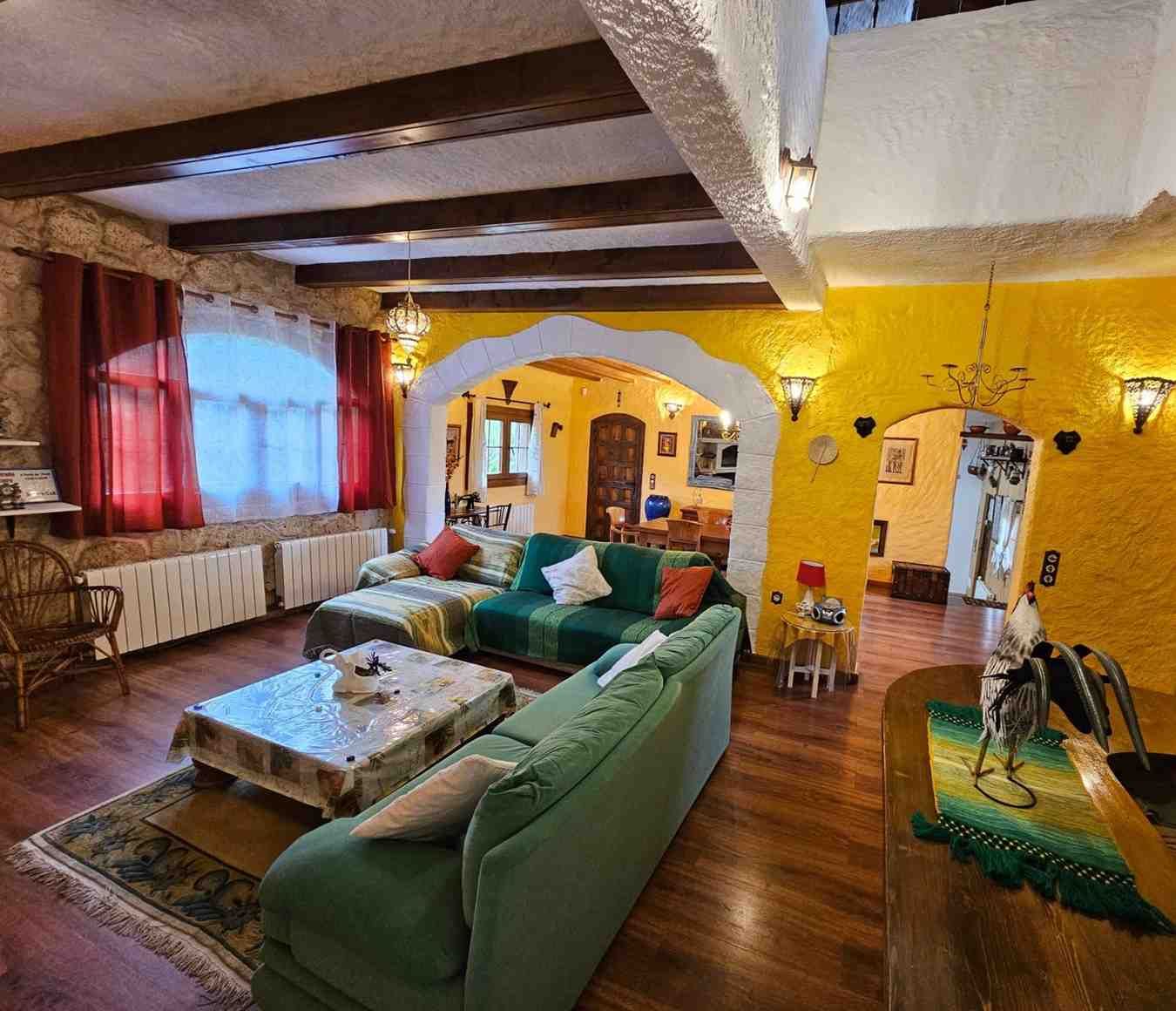 Acogedora sala de estar con pisos de madera, paredes amarillas y un sofá seccional verde.