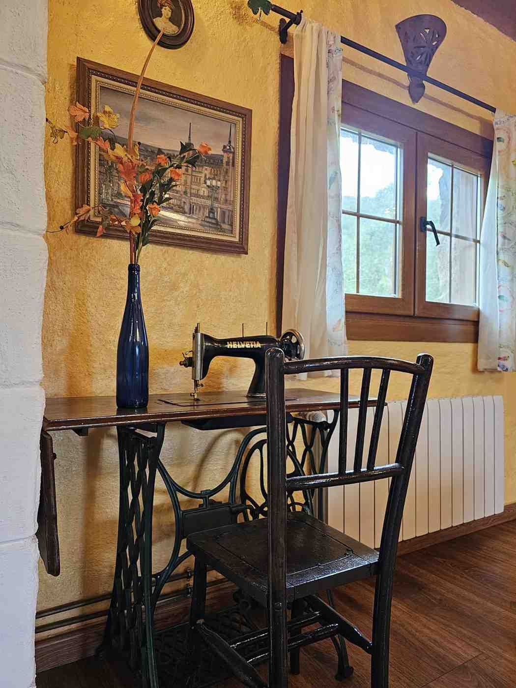 Máquina de coser antigua con arte enmarcado, flores y una ventana.