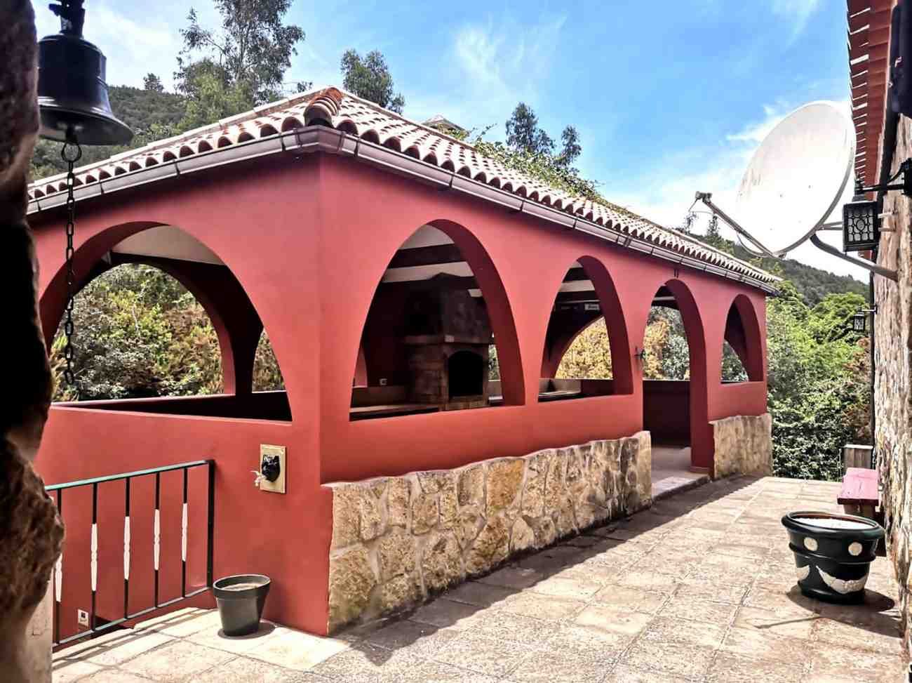 Estructura exterior pintada de rojo con aberturas arqueadas, base de piedra