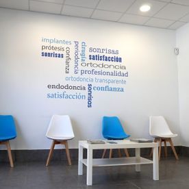 Una sala de espera con sillas azules y blancas y una mesa de café.