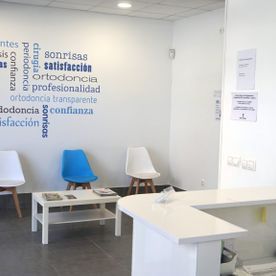 Una sala de espera con sillas, una mesa y un cartel en la pared.