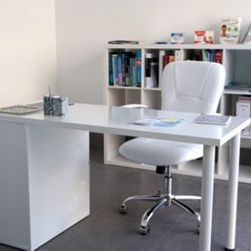 Un escritorio blanco y una silla en una habitación con estanterías.