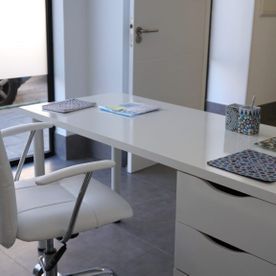 Una silla blanca está delante de un escritorio blanco.