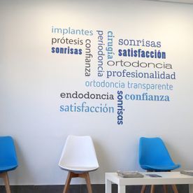 Una sala de espera con sillas azules y una pared con palabras en español.