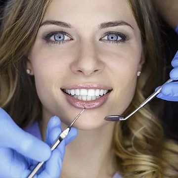 Una mujer está siendo examinada por un dentista.