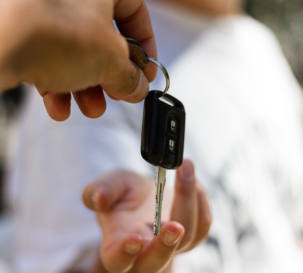 Eine Person gibt einer anderen Person einen Autoschlüssel