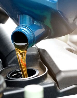 Eine Flasche Öl wird in einen Automotor gegossen
