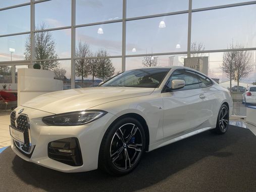 Ein weißes BMW 4er Coupé steht in einem Ausstellungsraum.