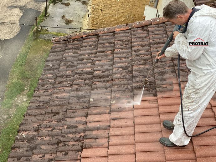 Un couvreur qui nettoie une toiture