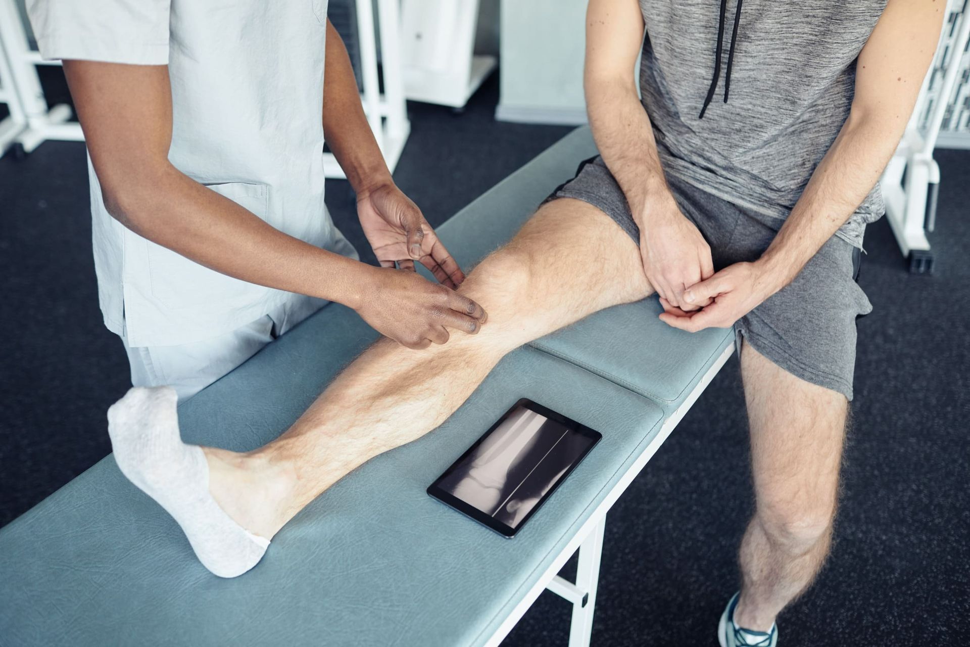 Un hombre está sentado en una mesa mientras una enfermera examina su pierna.