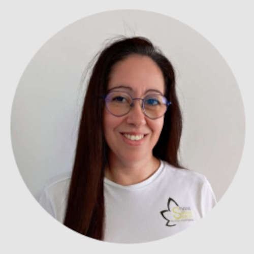 Una mujer que lleva gafas y una camisa blanca sonríe en un círculo.
