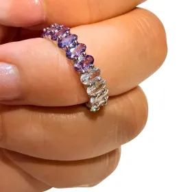 Mano sosteniendo un anillo de plata con piedras preciosas moradas y transparentes en primer plano.
