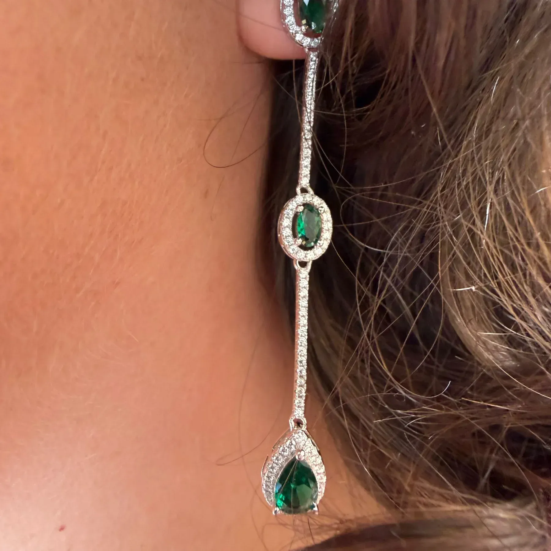 Pendientes largos de plata con esmeraldas que se llevan en el cuello y el cabello.