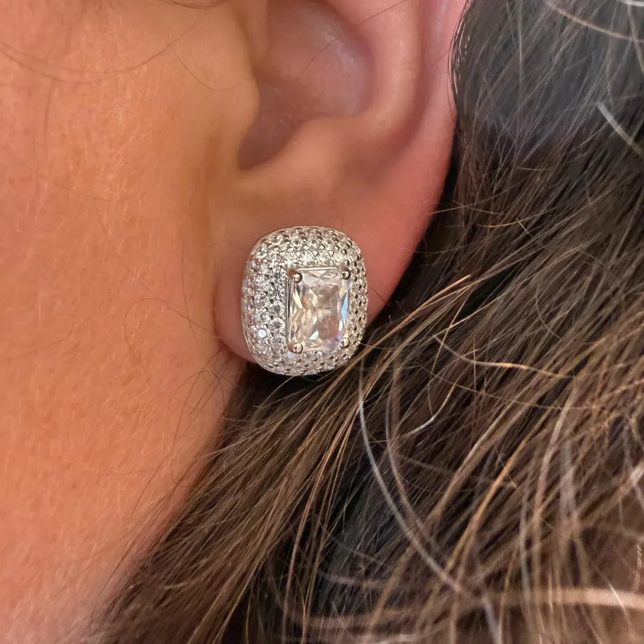 Primer plano de un brillante pendiente de diamantes en una oreja con cabello cerca.