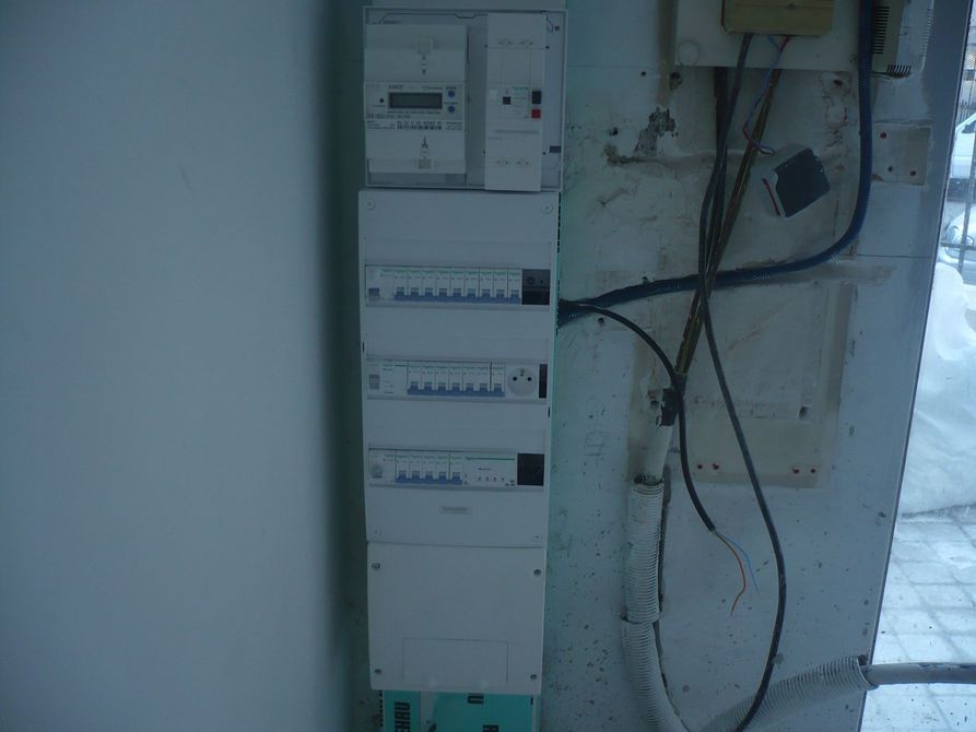 Tableau électrique avec câblage fixé au mur d'une buanderie.