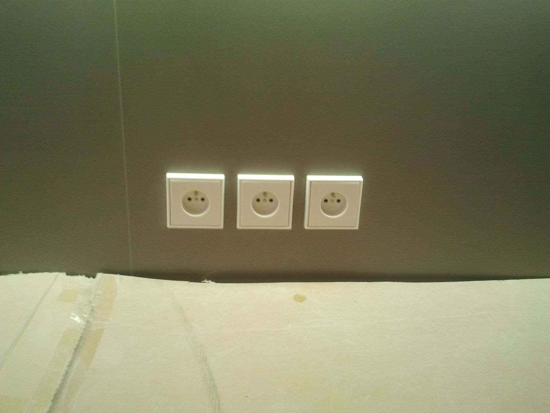 Trois prises murales au-dessus d'un lit ou d'une table.