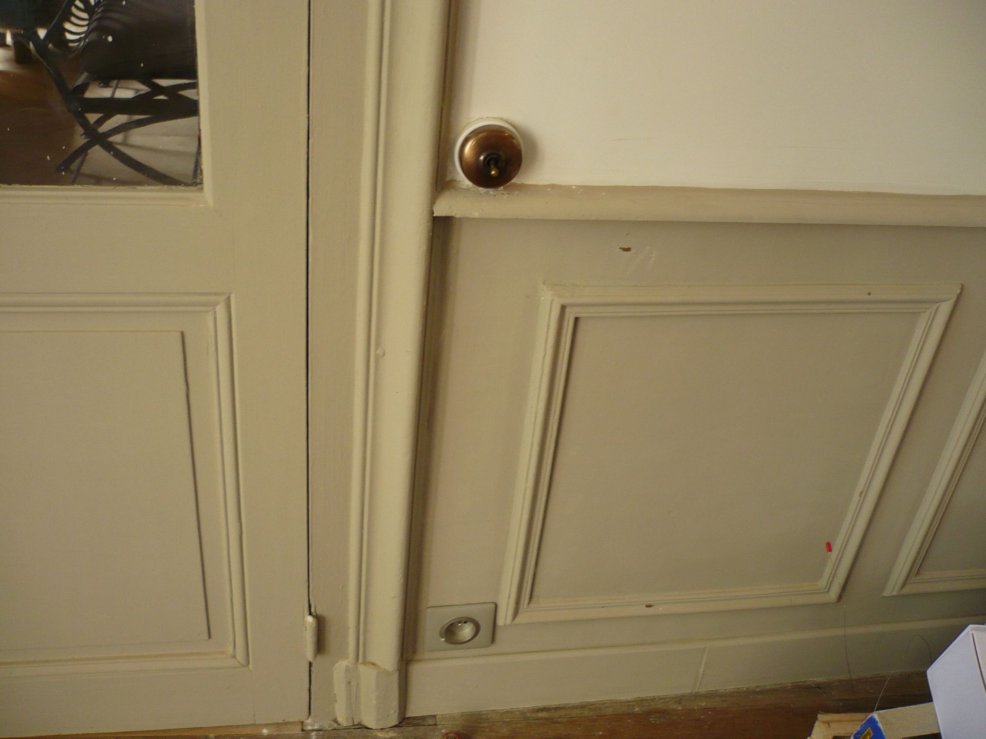 Gros plan sur une porte intérieure couleur crème avec des panneaux en relief et des poignées en laiton.