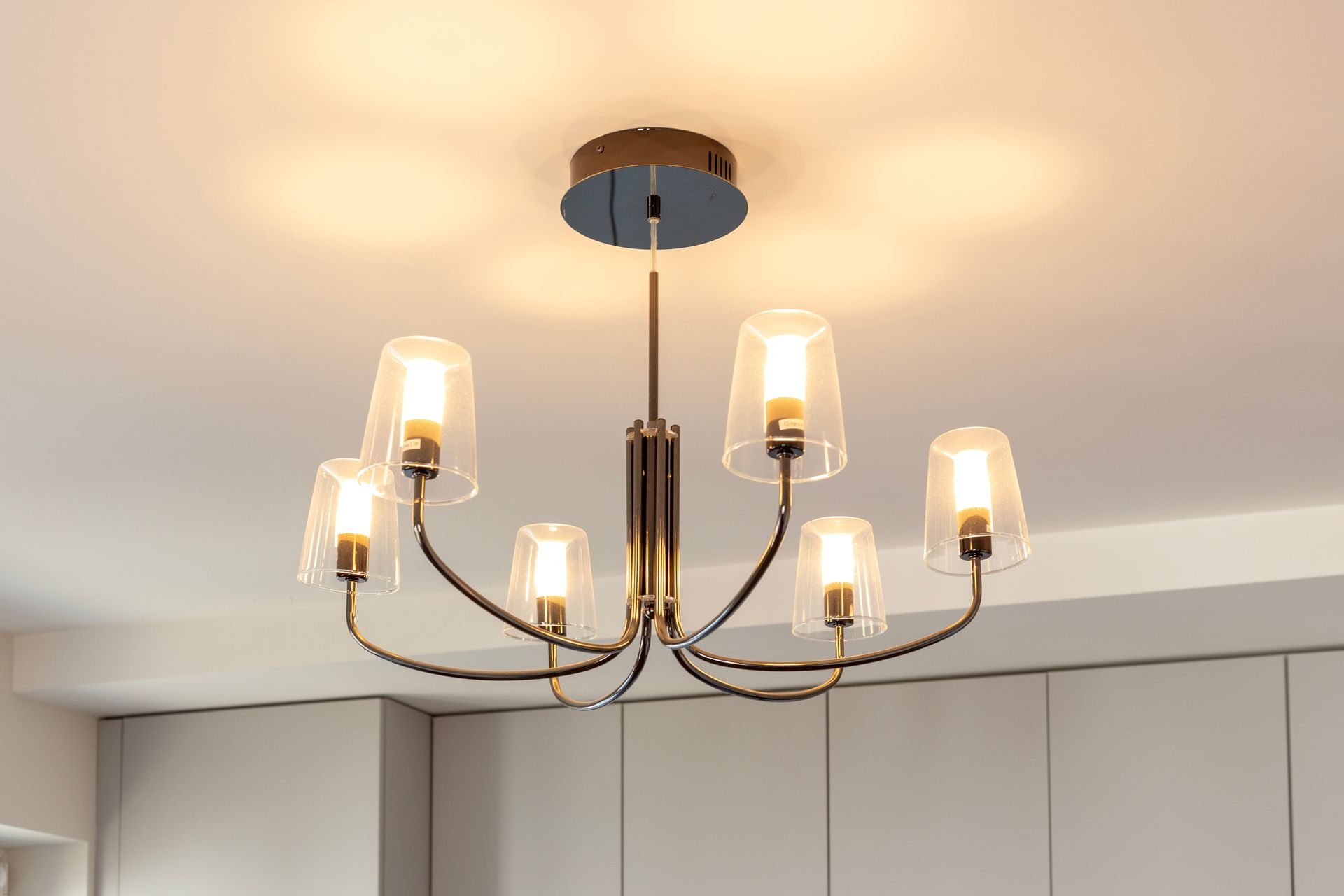 Lustre moderne en laiton avec abat-jour en verre dépoli suspendu au plafond d'une pièce.