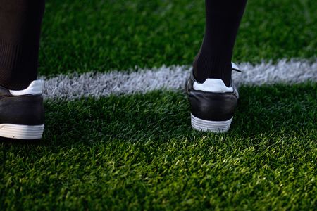 Un primer plano de los pies de un jugador de fútbol en un campo de fútbol.